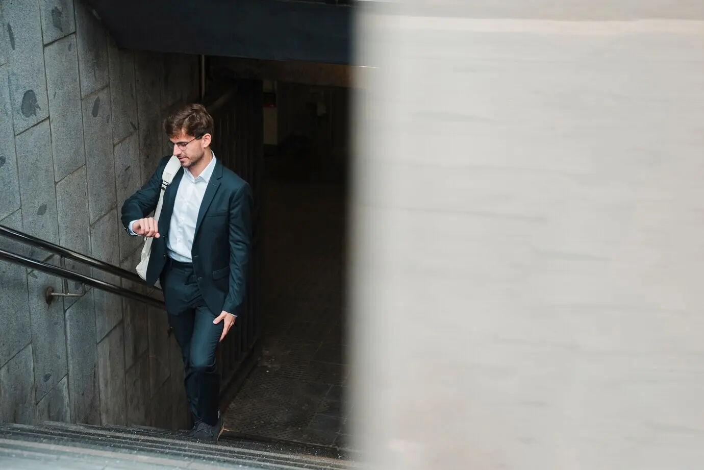 Ein Mann geht auf einer U-Bahntreppe und prüft die Zeit.